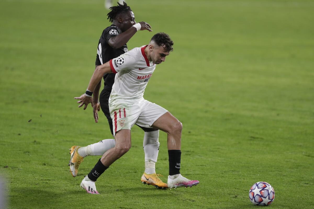 Rennes' Jeremy Doku, left, vies for the ball with Sevilla's Munir El Haddadi  