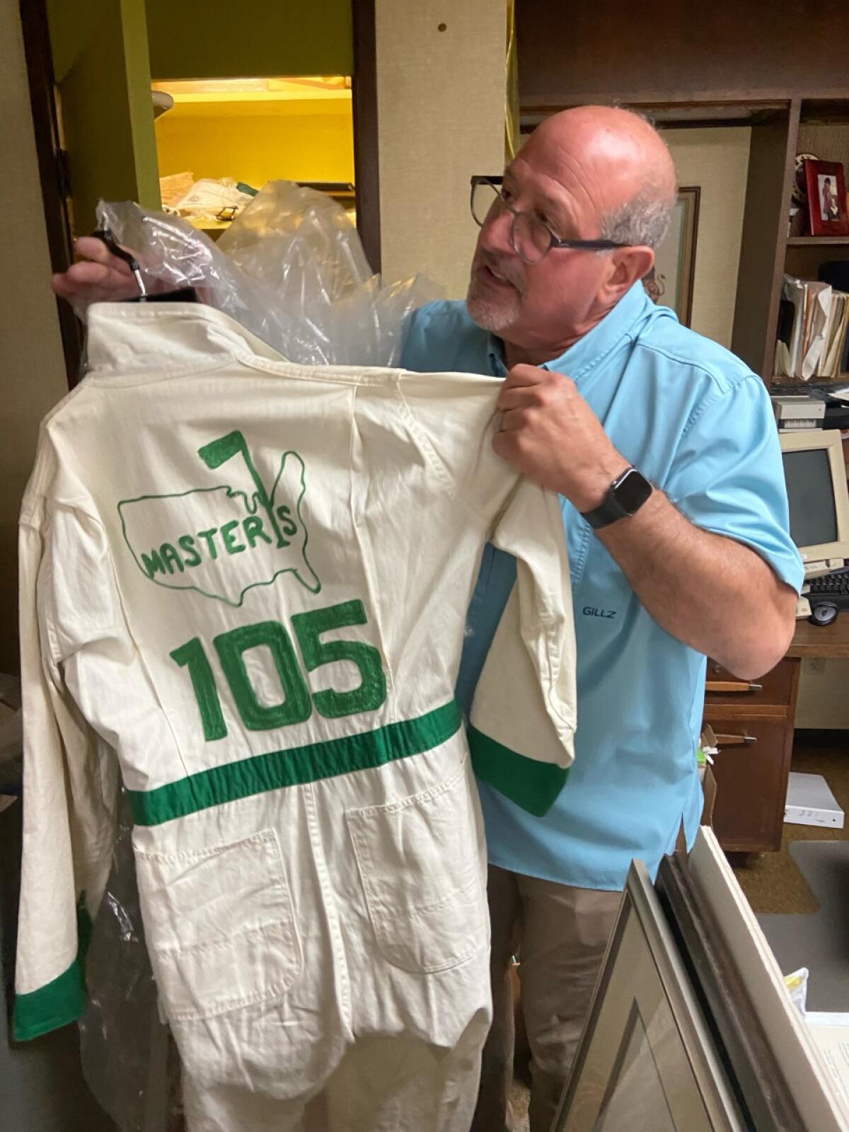 Fred Daitch, whose family made the caddie uniforms for more than a half-century, holds a vintage version.