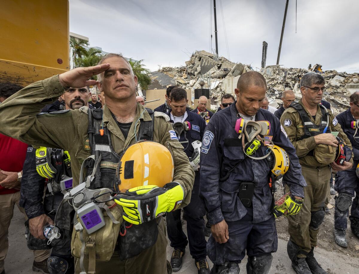 A member of the Israeli search and rescue team salutes in front of the rubble that once was Champlain Towers South.