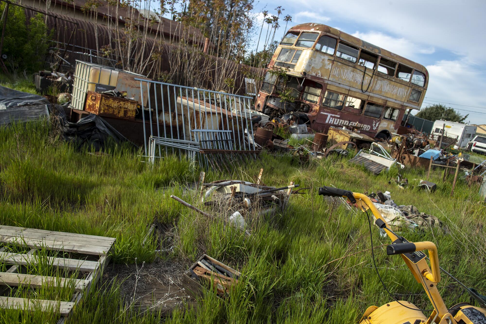 A weedy field strewn with old cars, junk and antiques.