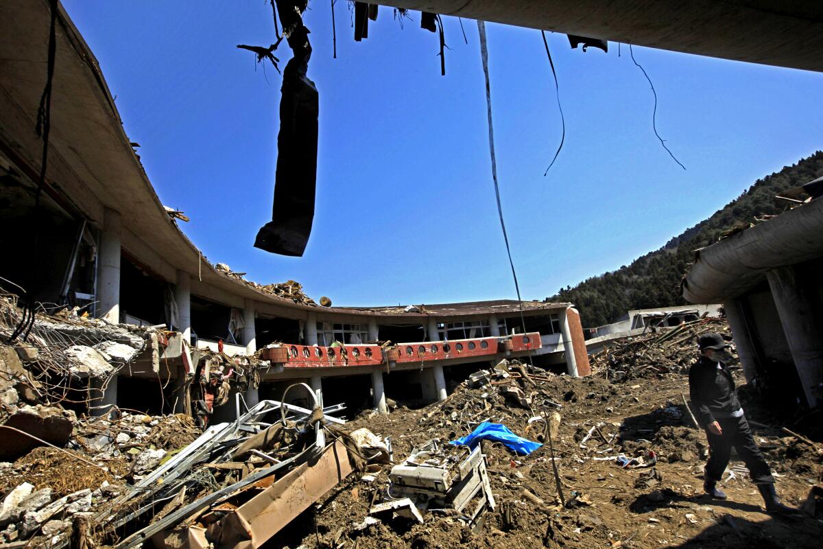 A man walks through the debris at Okawa Elementary School, devastated by an earthquake and tsunami