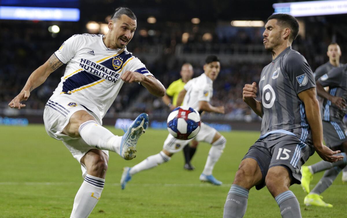 Galaxy forward Zlatan Ibrahimovic attempts a shot while defended by Minnesota's Michael Boxall during the first half Sunday.