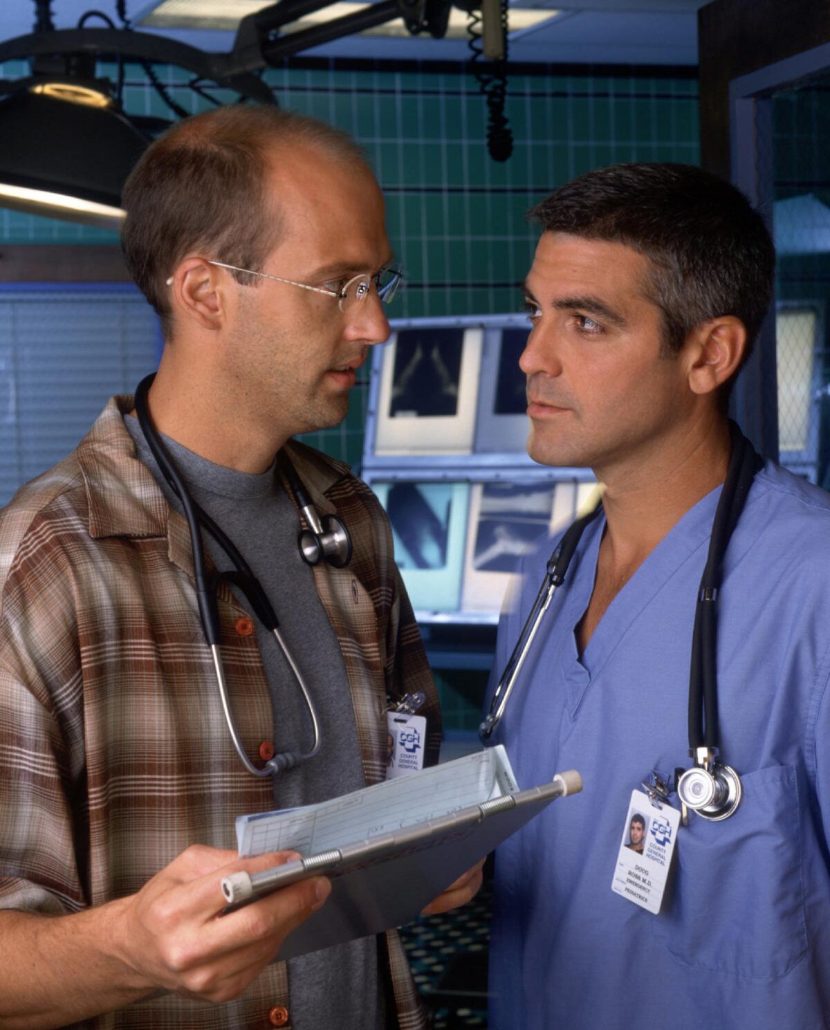Two doctors look at each other during a consultation in a scene from TV series “ER”