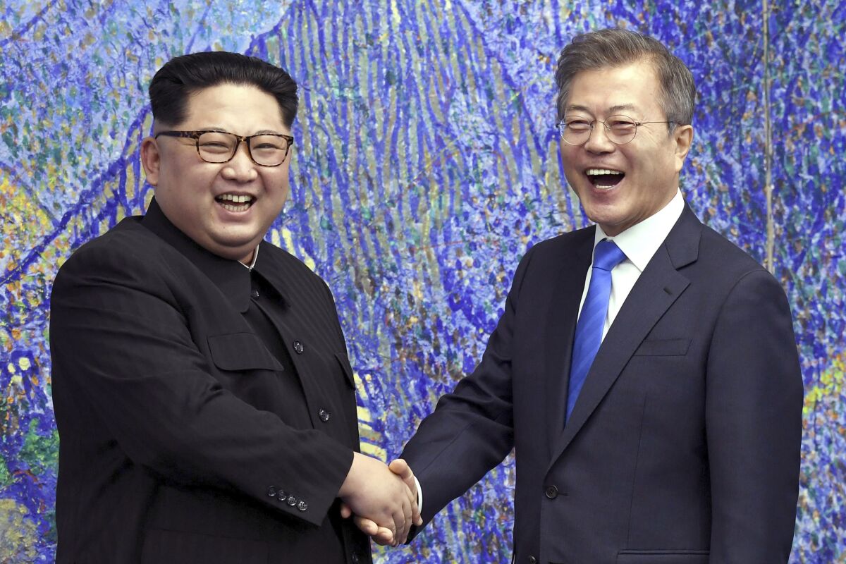 Two smiling men shake hands.