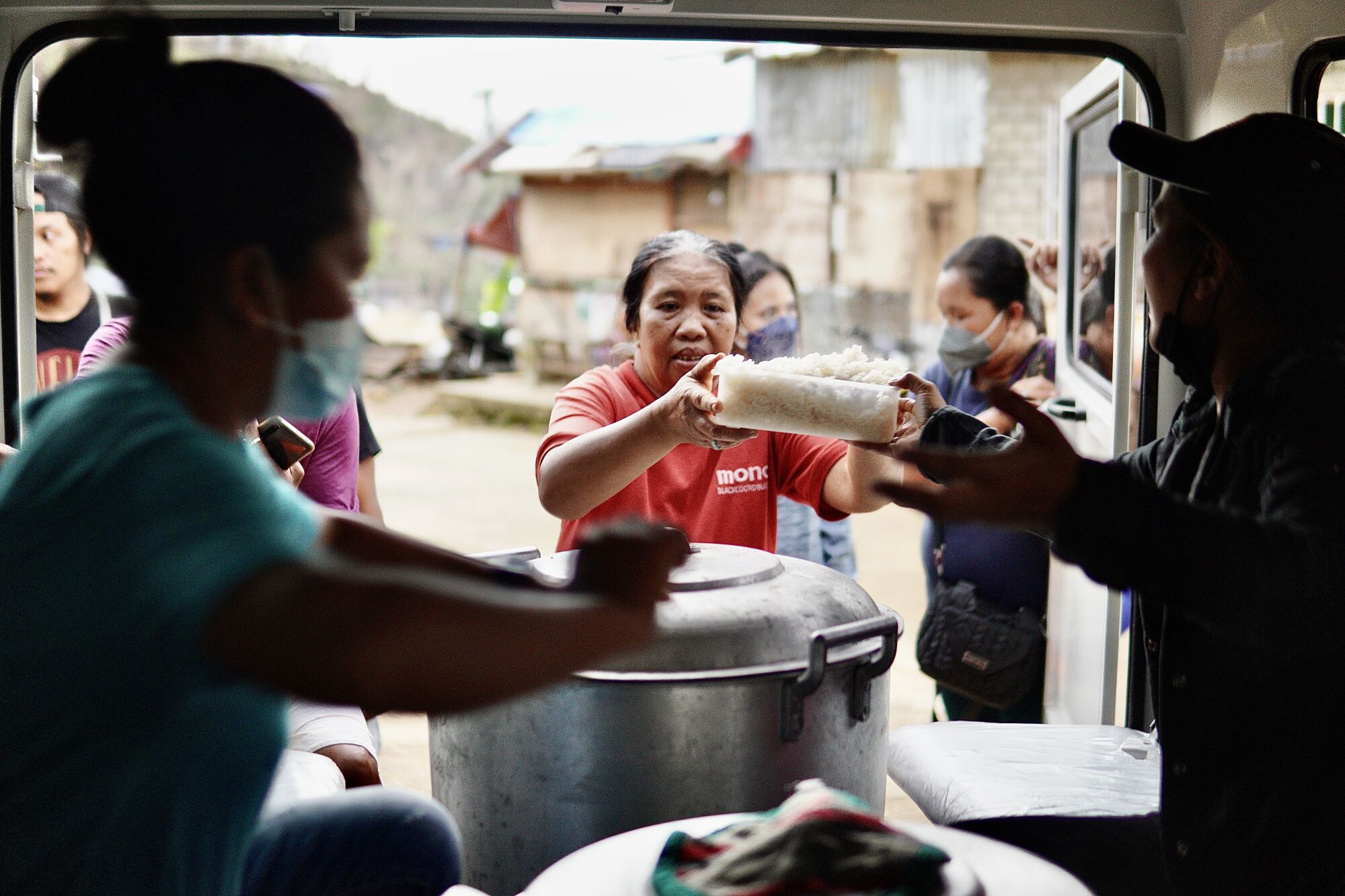 ARMK volunteers give food to residents from the back of a vehicle.