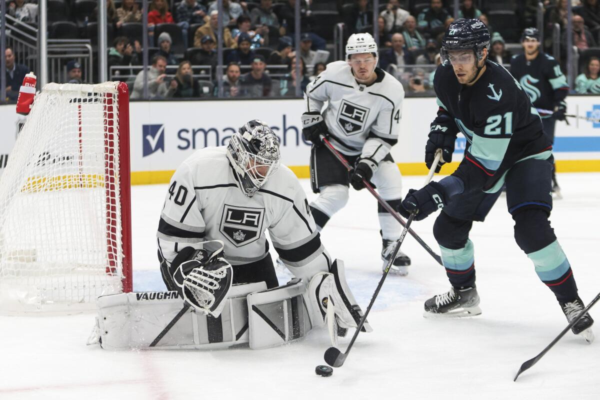 Kings goaltender Cal Petersen watches the puck as Seattle Kraken center Alex Wennberg tries to score.