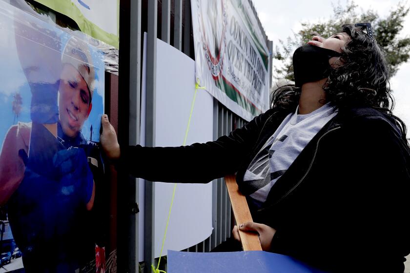 GARDENA, CALIF. - JUNE 19, 2020. Jennifer Guardado touches a picture of her brother, Andres Guardado, as she grieves Firiday afernoon, June 19, 2020, at the location in Gardena where the 18-year-old L:atino youth was shot and killed by L.A. County Sheriff's deputies. Family members and community activists said Guardado was working as a security guard in a body shop when the violent encounter with police happened on Thursday, June 18, 2020. (Luis Sinco/Los Angeles Times)