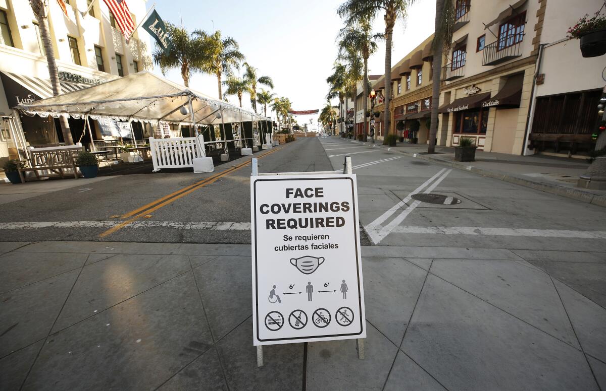 A sign in in front of shops in Ventura reads, "Face coverings required"