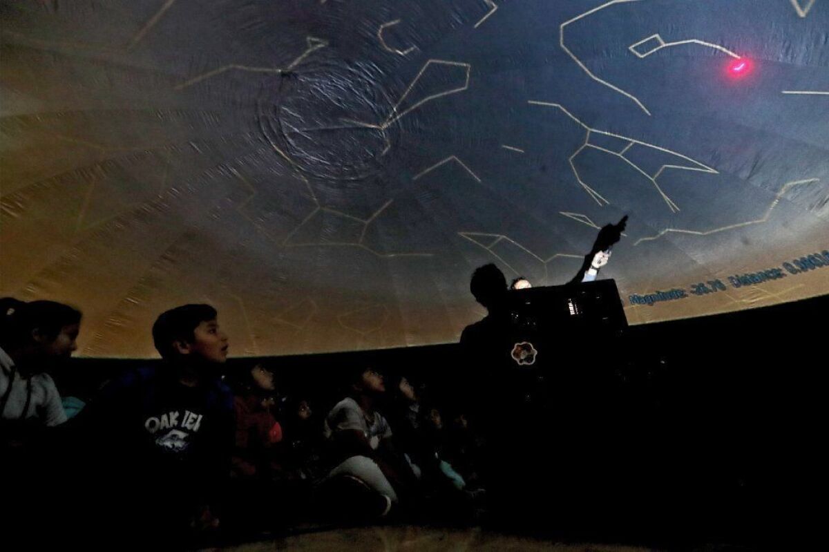 Mario Tomic, an educational performer with Mobile Ed Productions, uses a laser pointer to show students at Oak View Elementary School various constellations projected in an inflatable planetarium.