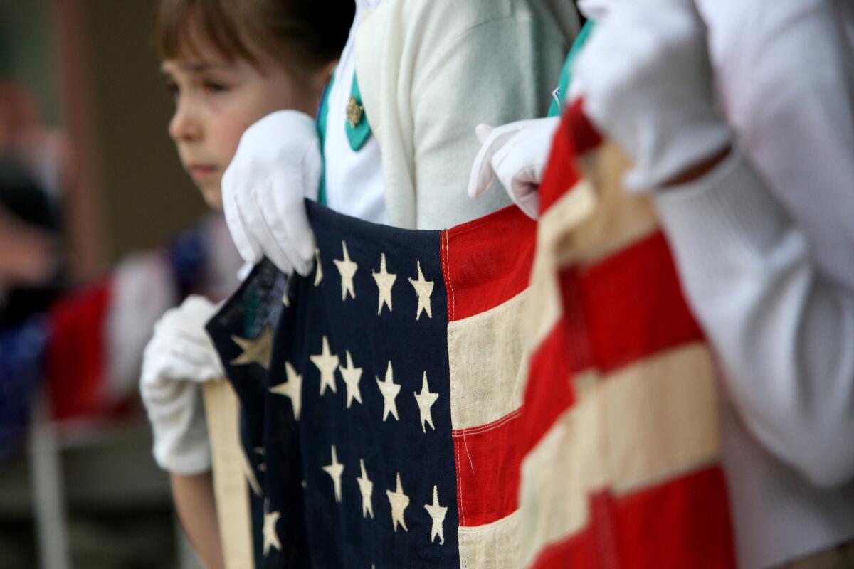Local girl scouts hold an old 48-star US flag at the annual Memorial Day service at Memorial Park in La Cañada Flintridge on Monday, May 25, 2015.