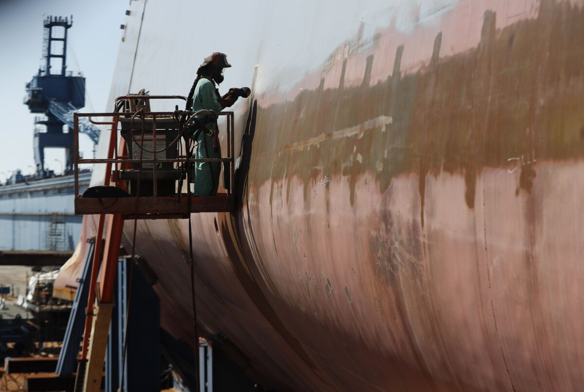 A welder works on a ship hull.