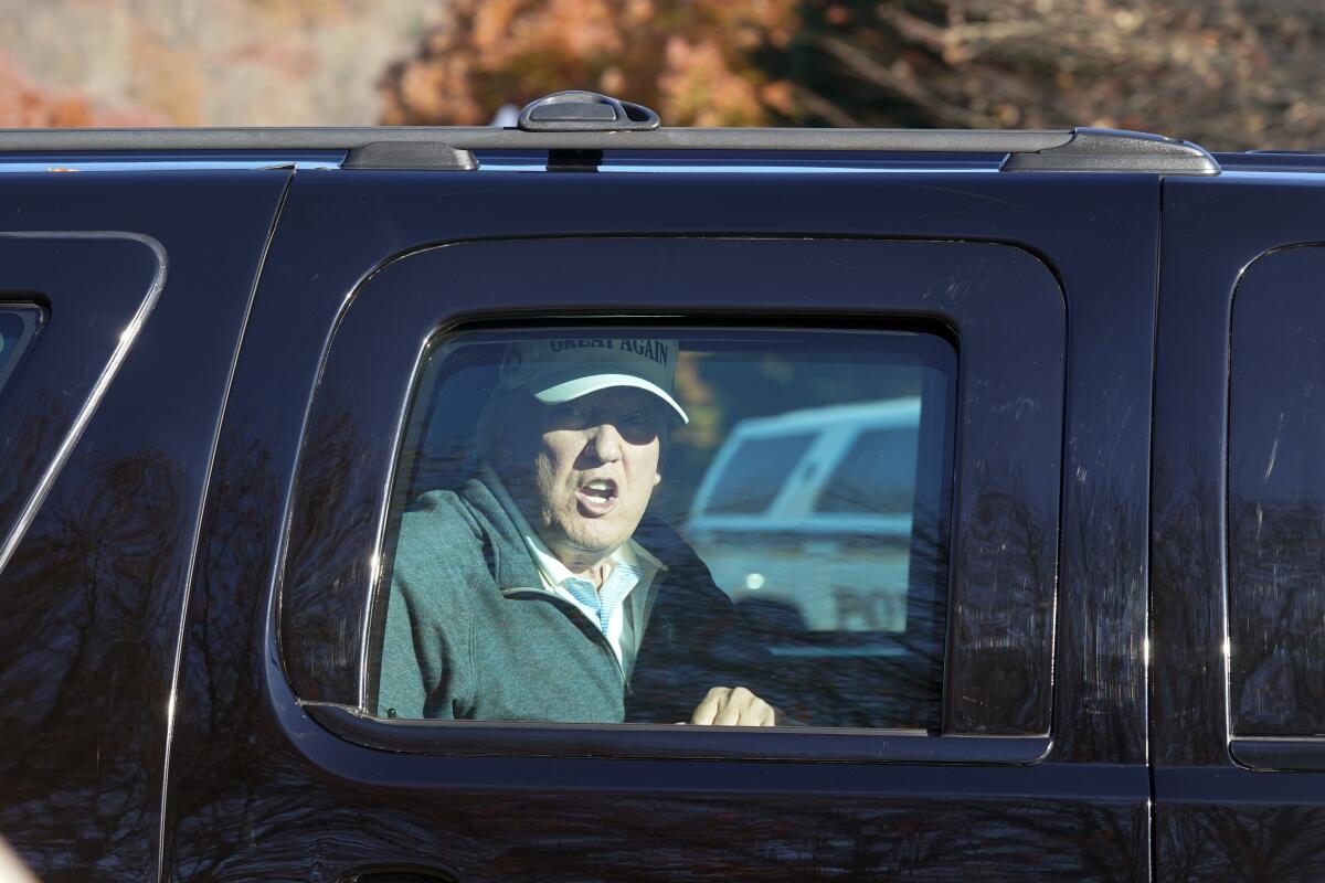 President Trump looks at supporters from his vehicle as he leaves Trump National Golf Club in Sterling, Va.