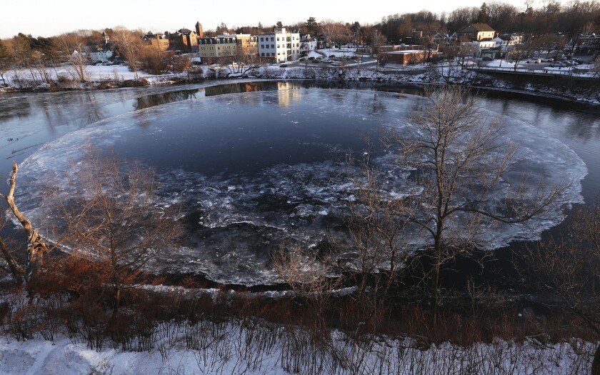 The Westbrook ice disk has returned to the Presumpscot River below Saccarappa Falls, Tuesday, Jan. 11, 2022, in Westbrook, Maine. The disk has begun to form in the Presumpscot River, where it partially formed in 2020 but failed to draw a worldwide audience like in its first appearance in 2019. (Ben McCanna/Portland Press Herald via AP)