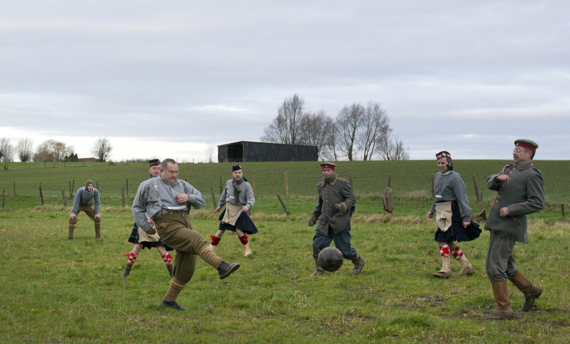 Reenactors are dressed in World War I British and German uniforms as they kick around a soccer ball 