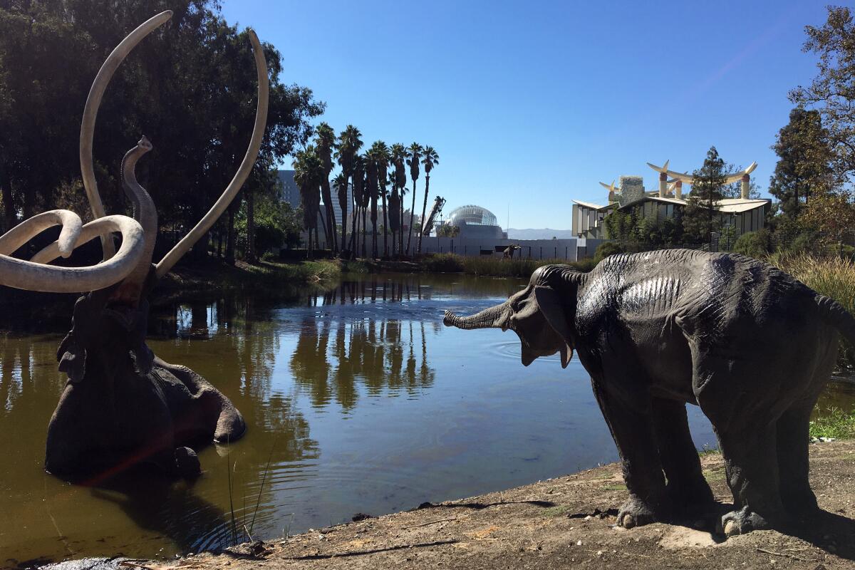 A mammoth statue in water next to another mammoth statue on the shore