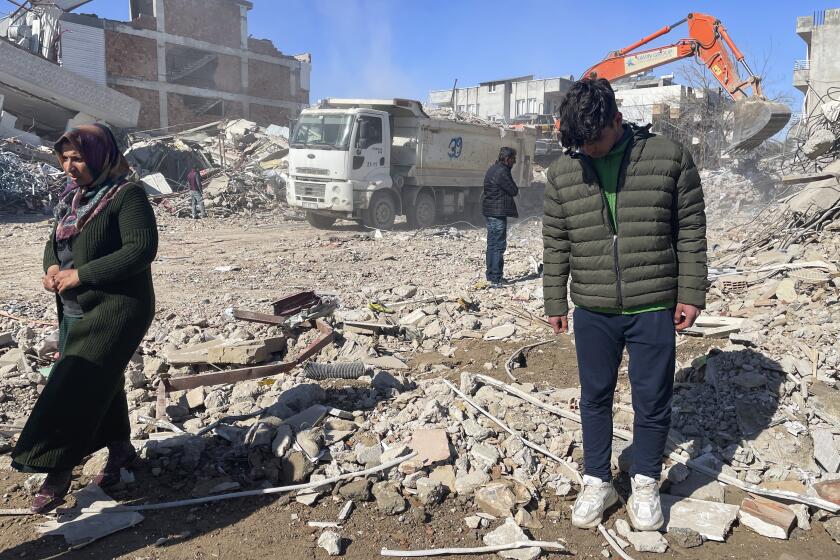Taha Erdem, 17, right, his mother Zeliha Erdem, left, and father Ali Erdem stand next to the debris from a building where Tahan was trapped after the earthquake of Feb. 6, in Adiyaman, Turkey, Friday, Feb. 17, 2023. Taha Erdem, a resident of southeastern Turkey's Adiyaman, is one of the hundreds of survivors pulled out of collapsed buildings after the Feb. 6 powerful quake. Erdem, who is 17, filmed himself on his phone while stuck and sandwiched between concrete in what he thought would be his last words. (AP Photo/Mehmet Mucahit Ceylan)
