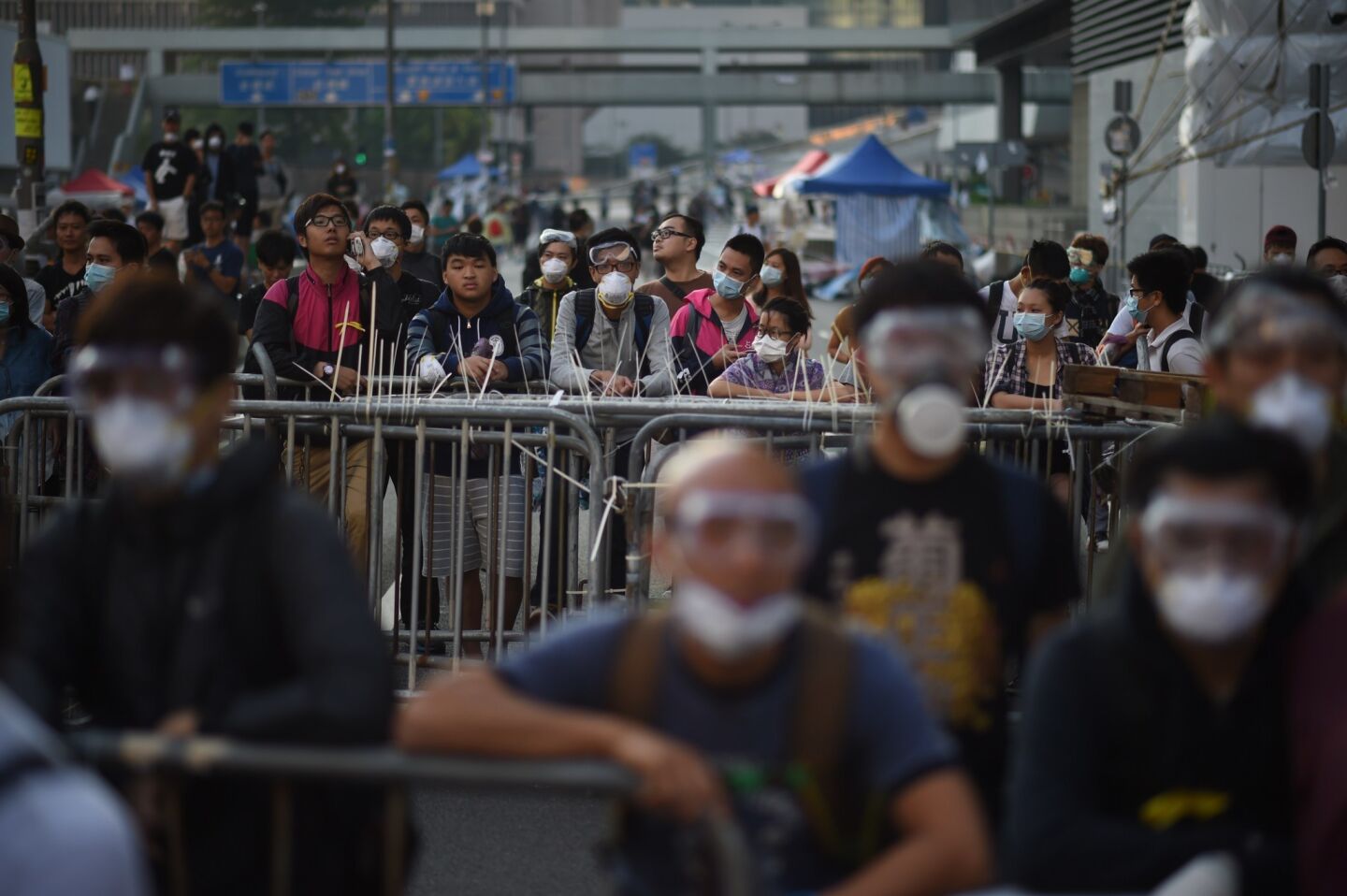 Pro-democracy protesters stand next to barricades as police officers gather in the central district of Hong Kong on Oct. 13.