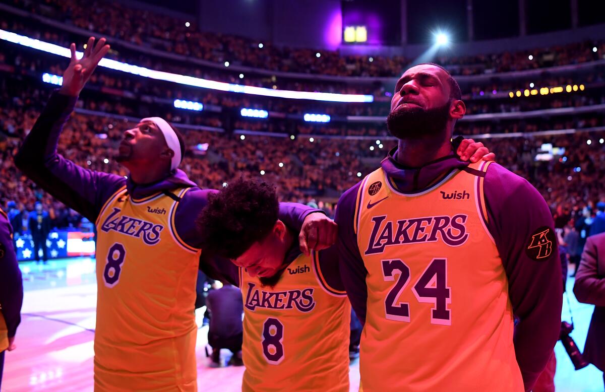 Kentavious Caldwell-Pope points skyward, and Quin Cook and LeBron James close their eyes, on the basketball court.