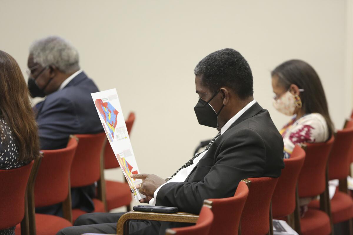 Man in a facemask sits in a red chair while looking at a map