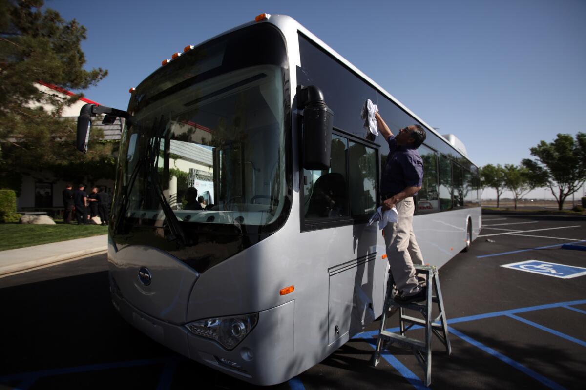 Joaquin Clara Lopez of Palmdale washes the windows of a new bus before a press conference where BYD and the city of Lancaster announced a new manufacturing facility in Lancaster.