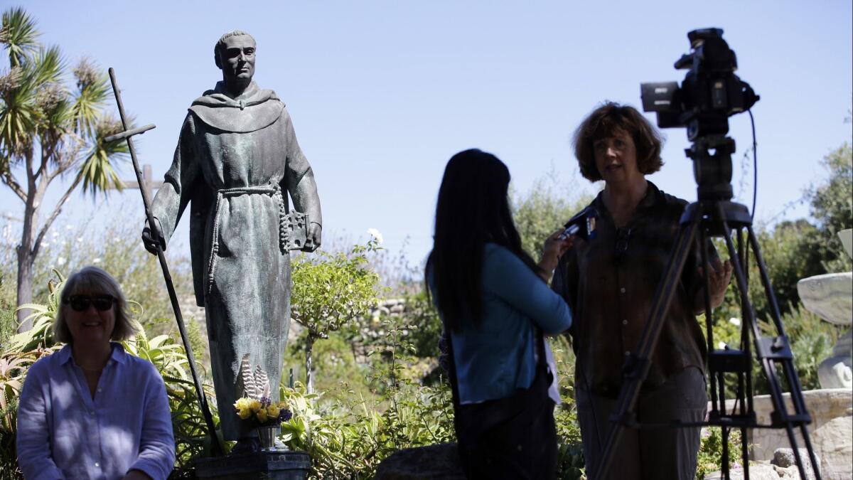 An interview is conducted next to a statue of Junipero Serra at the Carmel Mission in Carmel-By-The-Sea, Calif.