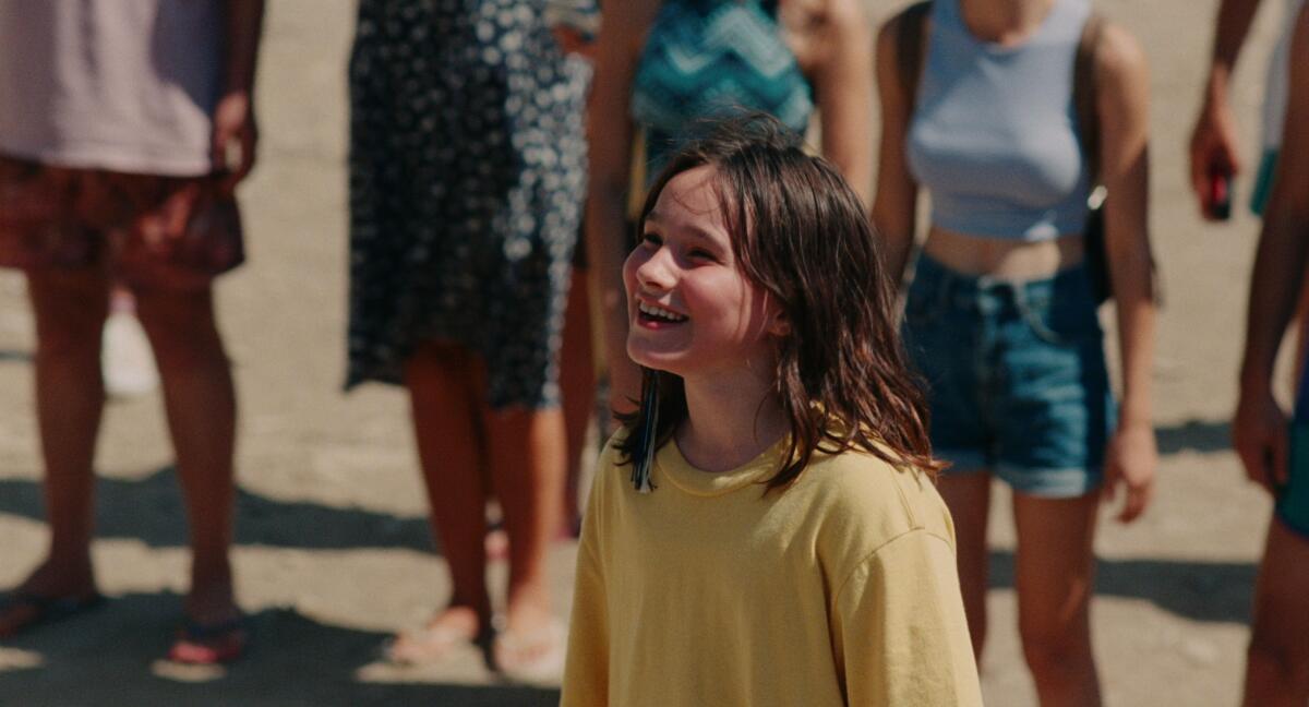 A girl in a yellow shirt smiles 