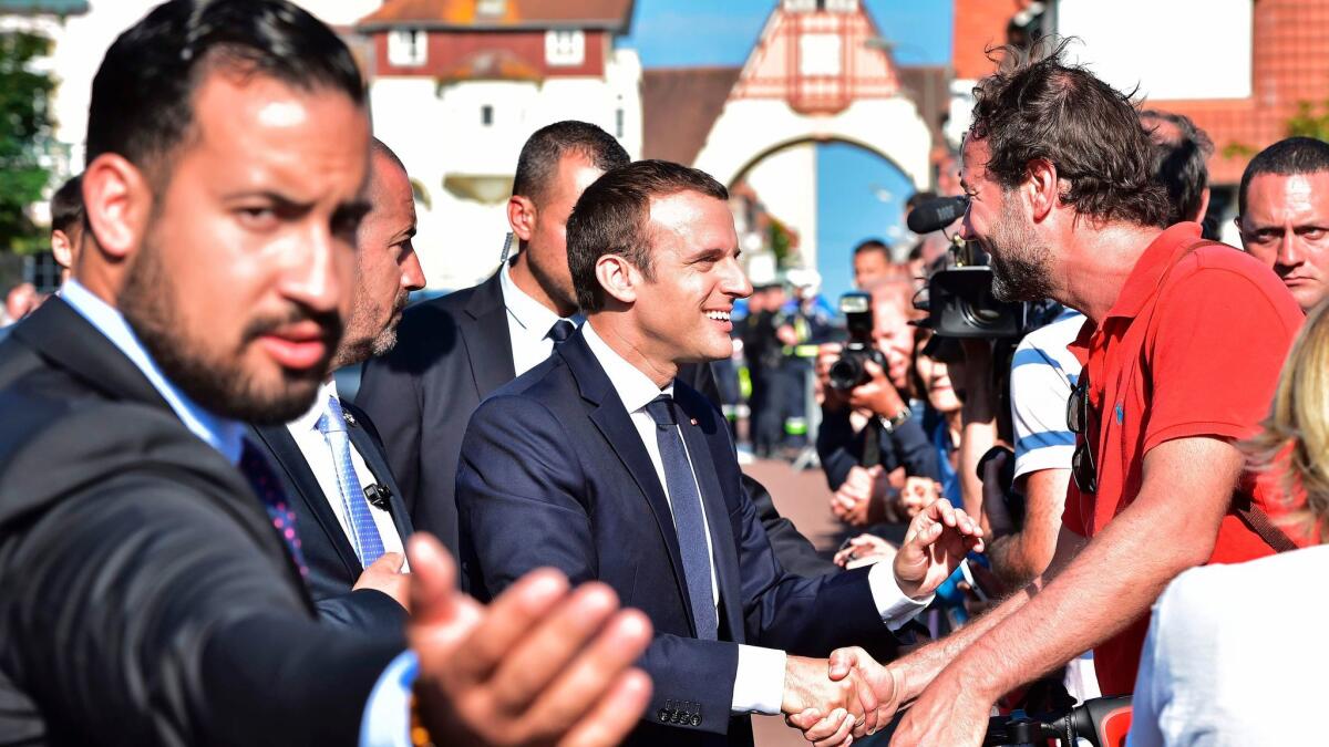 French President Emmanuel Macron, center, shakes hands with people after voting in Le Touquet, northern France, during the second round of parliamentary elections on June 18, 2017.