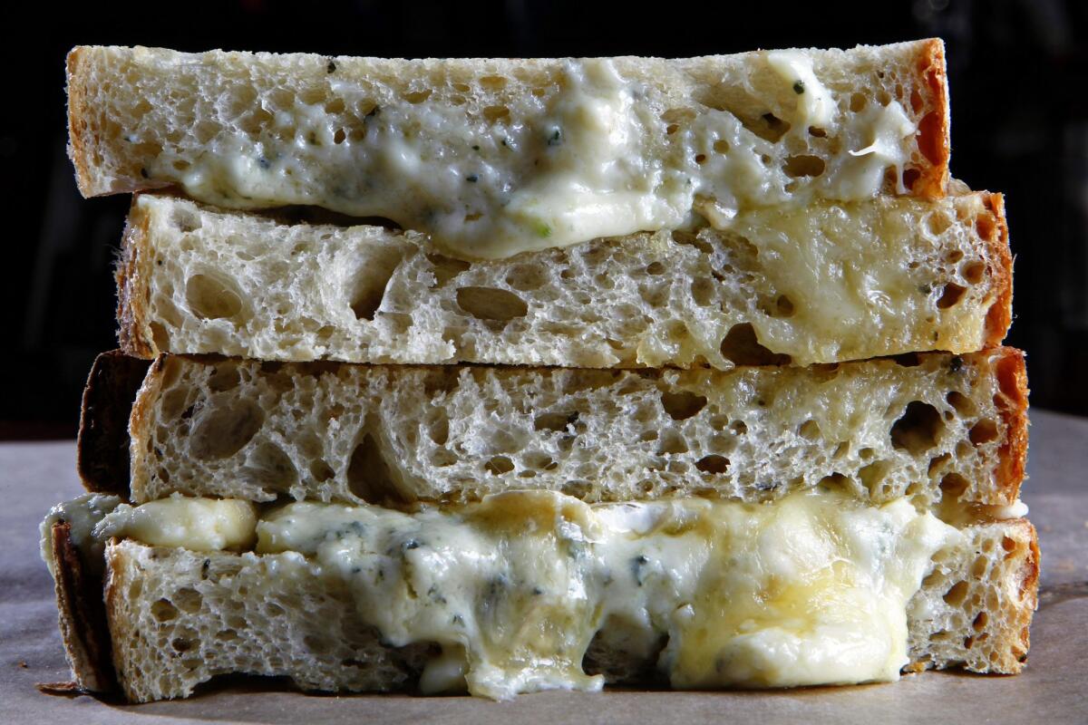 Un Sándwich de Queso Casi Asado a la Parrilla, de la panadería, que contiene triple queso brie francés y queso Gorgonzola, sobre pan de aceite de oliva y romero tostado al horno.