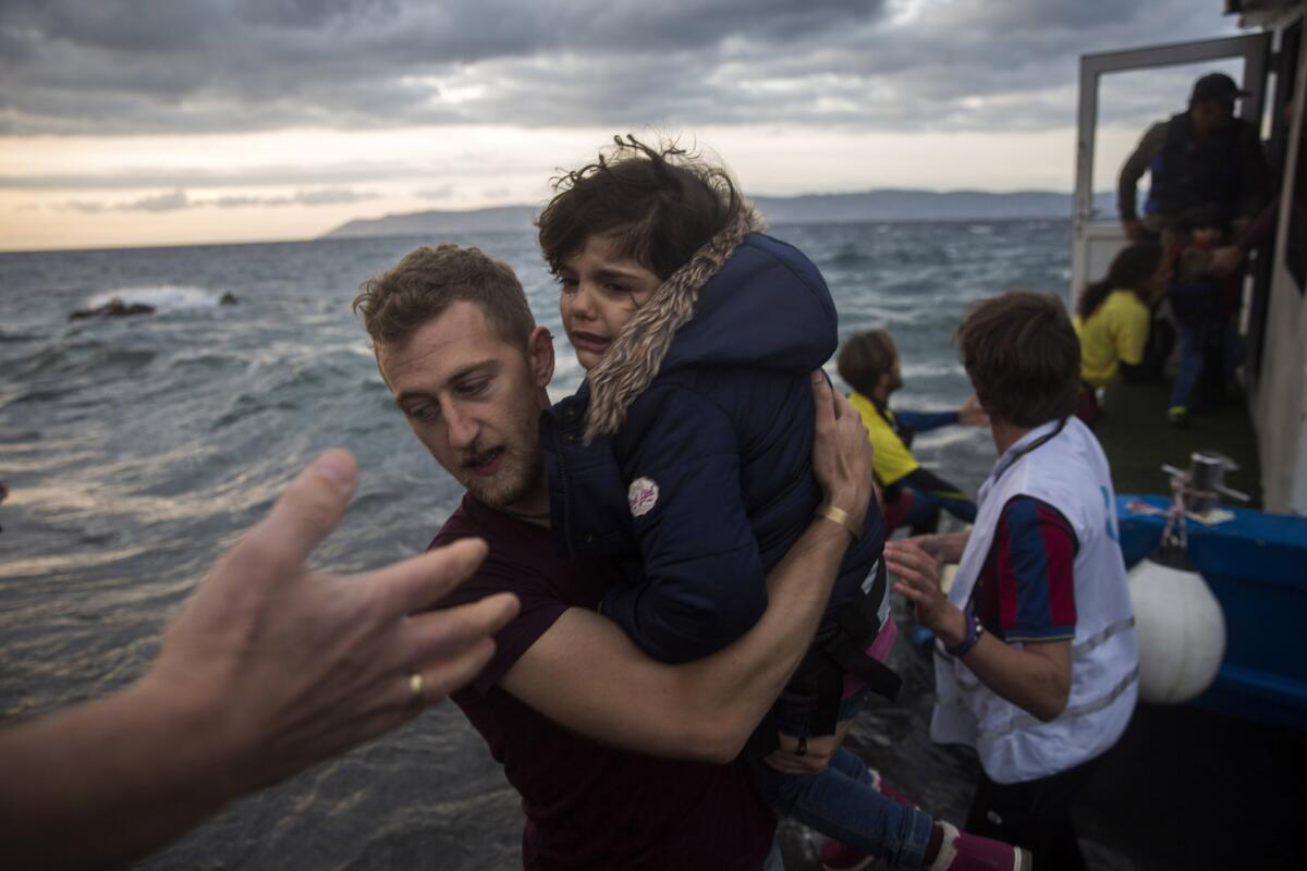 A photographer helps a migrant girl disembark on the Greek island of Lesbos after arriving with around 125 people on a boat from Turkey on Oct. 29.