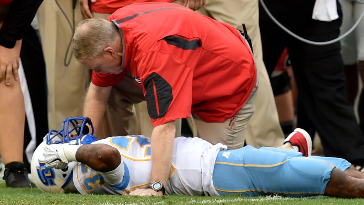 Southern receiver Devon Gales is able to move his hands as Ron Caruso, Georgia senior associate athletic director for sports medicine, checks on him before he was taken off the field on a stretcher.