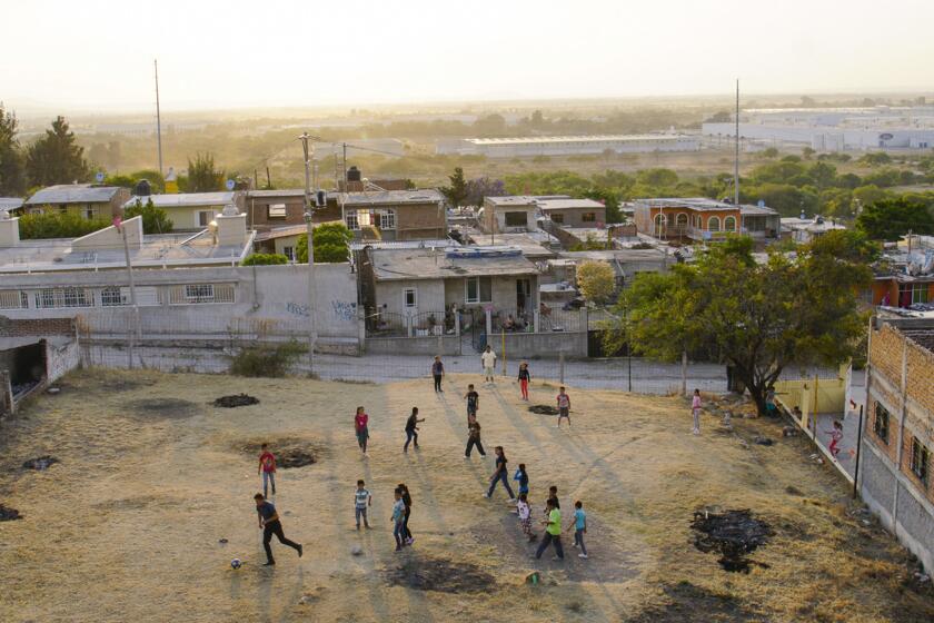 Residents of Lo De Juarez, a small community in Guanajuato play soccer. In the background is a Ford plant, one of the nearby auto factories that have transformed the townâs labor force and helped curb migration to the U.S.