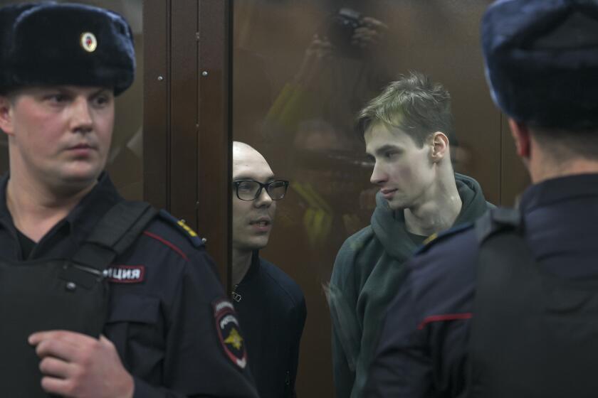 FILE - Artyom Kamardin, left, and Yegor Shtovba, right, stand behind a glass in a cage in a courtroom in Moscow, Russia, Thursday, Dec. 28, 2023. Artyom Kamardin was given a 7-year prison sentence Thursday for reciting verses against Russia's war in Ukraine, a tough punishment that comes during a relentless Kremlin crackdown on dissent. Yegor Shtovba, who participated in the event and recited Kamardin's verses, was sentenced to 5 1/2 years on the same charges. (AP Photo, File)