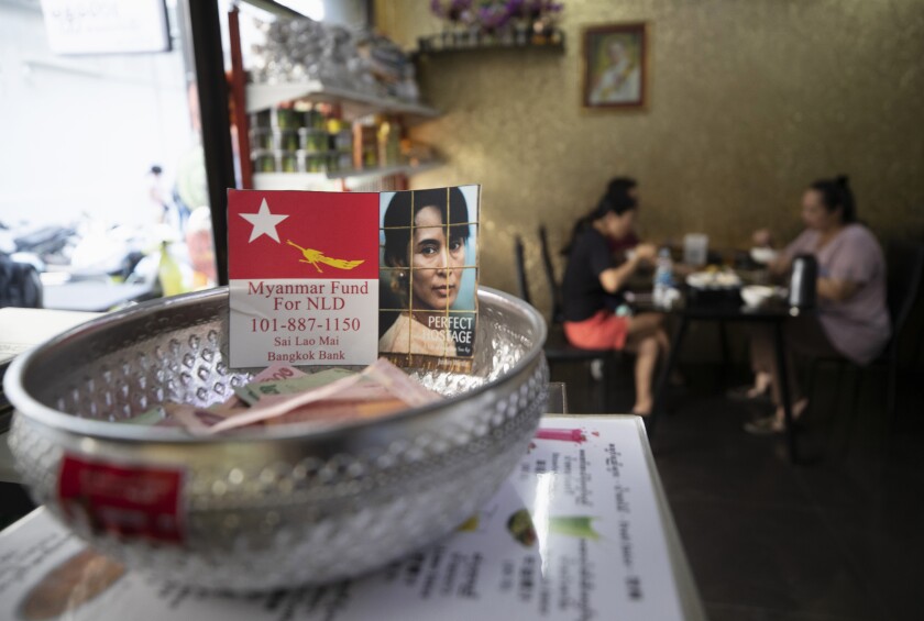 A donation bowl with an image of deposed Myanmar leader Aung San Suu Kyi is displayed on a stand as customers dine at Mandalay Food House in Bangkok, Thailand, Friday, Feb. 5, 2021. As expatriates from Myanmar around the world react to the military’s lightning takeover of their homeland, one restaurant in neighboring Thailand is offering food to help support members of Bangkok’s Myanmar community who want to take action against Monday’s coup. (AP Photo/Sakchai Lalit)