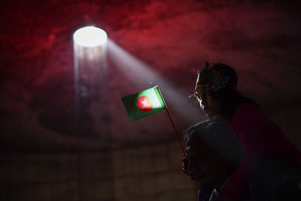 A Bangladeshi man carries his granddaughter holding their national flag inside the Museum of Independence during celebrations to mark 50 years of victory over Pakistan, at an event in Dhaka, Bangladesh, Thursday, Dec. 16, 2021. On Dec. 16, 1971, Pakistani soldiers surrendered to a joint India-Bangladesh force, formally making Bangladesh a new nation under the leadership of independence leader Sheikh Mujibur Rahman, the father of current Prime Minister Sheikh Hasina. (AP Photo/Mahmud Hossain Opu)