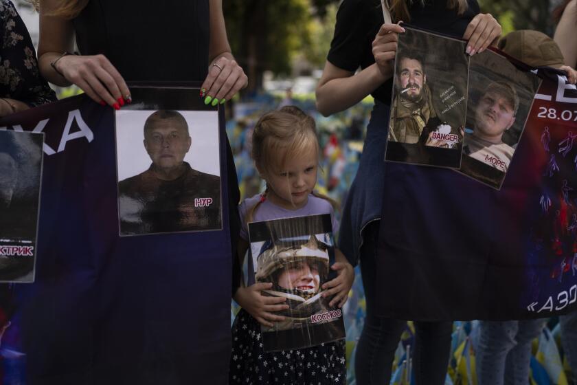 FILE - A girl holds a photo of a Ukrainian POW killed in the 2022 explosions at the Russian-controlled prison barracks in Olenivka, eastern Ukraine, during a memorial in Kyiv on July 29, 2023. An AP investigation interviewed survivors, family and investigators and obtained an internal U.N. analysis. All pointed to Russia as the culprit. (AP Photo/Jae C. Hong, File)