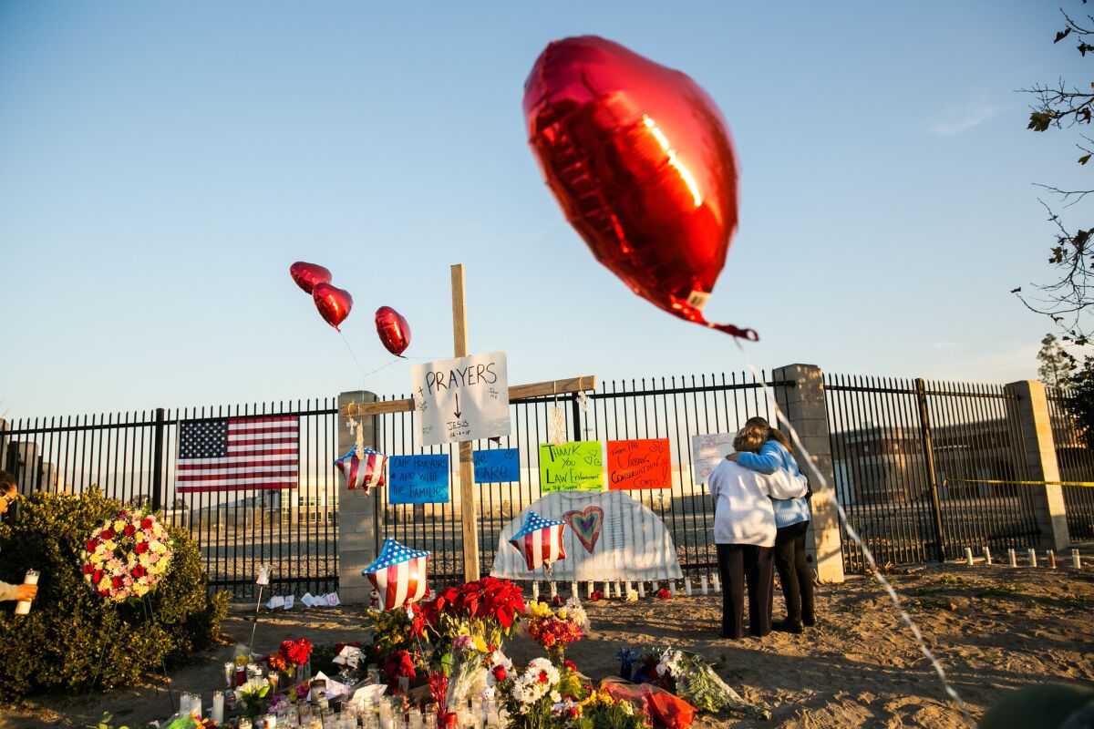 Two people quietly pay their respects Friday at the makeshift memorial erected for victims of Wednesday's shootings at the Inland Regional Center in San Bernardino.