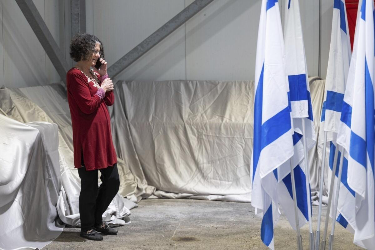 A woman speaks on a phone near Israeli flags. 