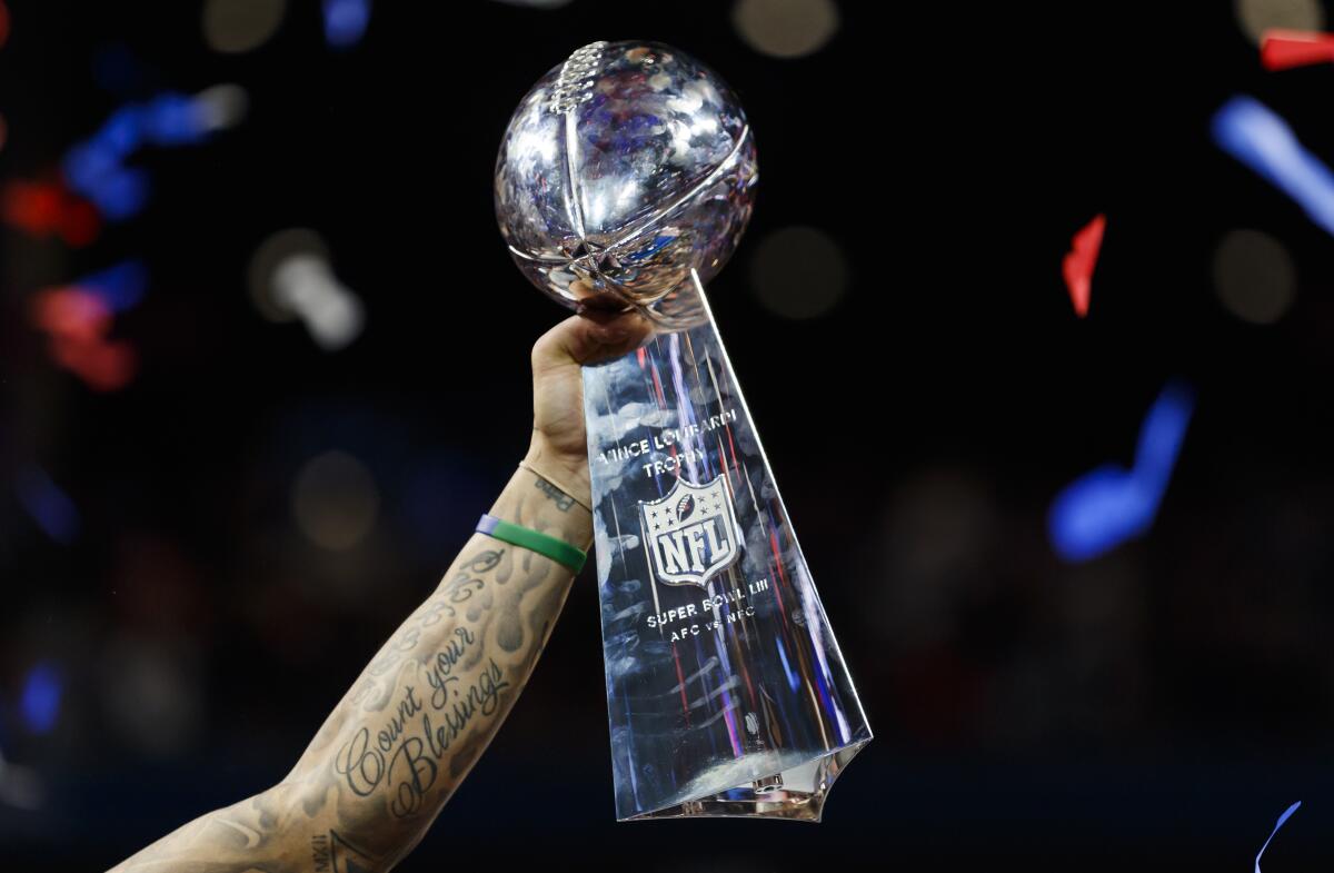The Vince Lombardi Trophy is held up with confetti falling.