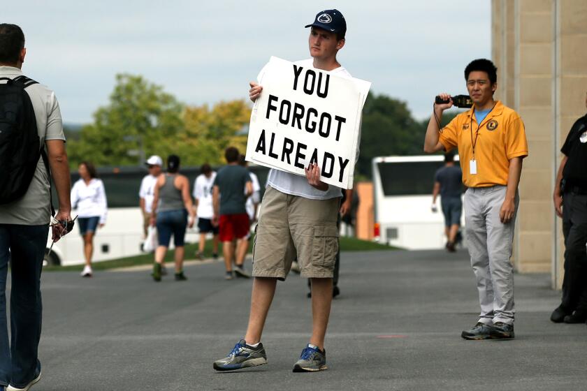 Andrew Limauro holds a sign outside Beaver Stadium protesting the school's decision to honor former head coach Joe Paterno on Saturday.