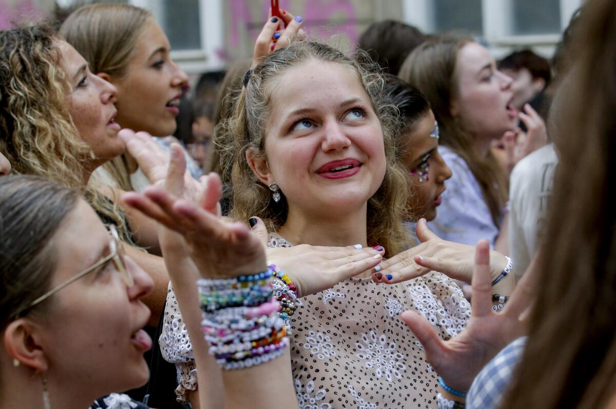 Swifties, wearing friendship bracelets, gather and sing in Vienna's city center. 