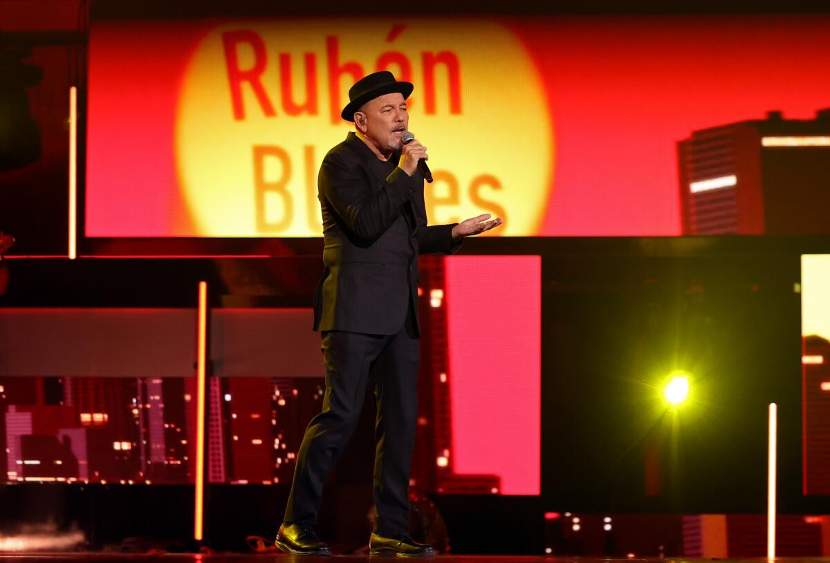 A man in a pork pie hat performs onstage