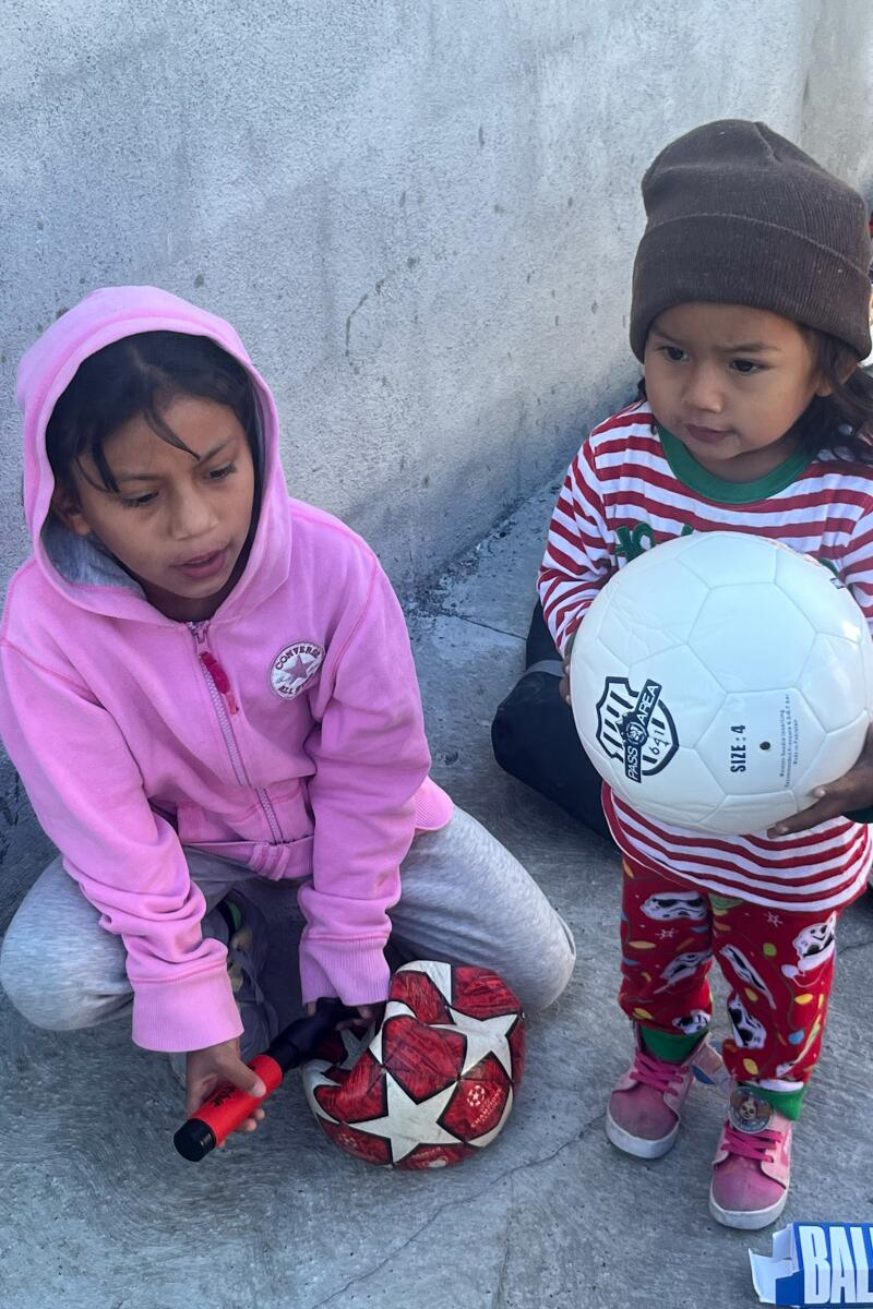 Valeri and her sister, Grace, not yet 2, pump soccer balls before practice at an immigrant shelter in Reynosa, Mexico.