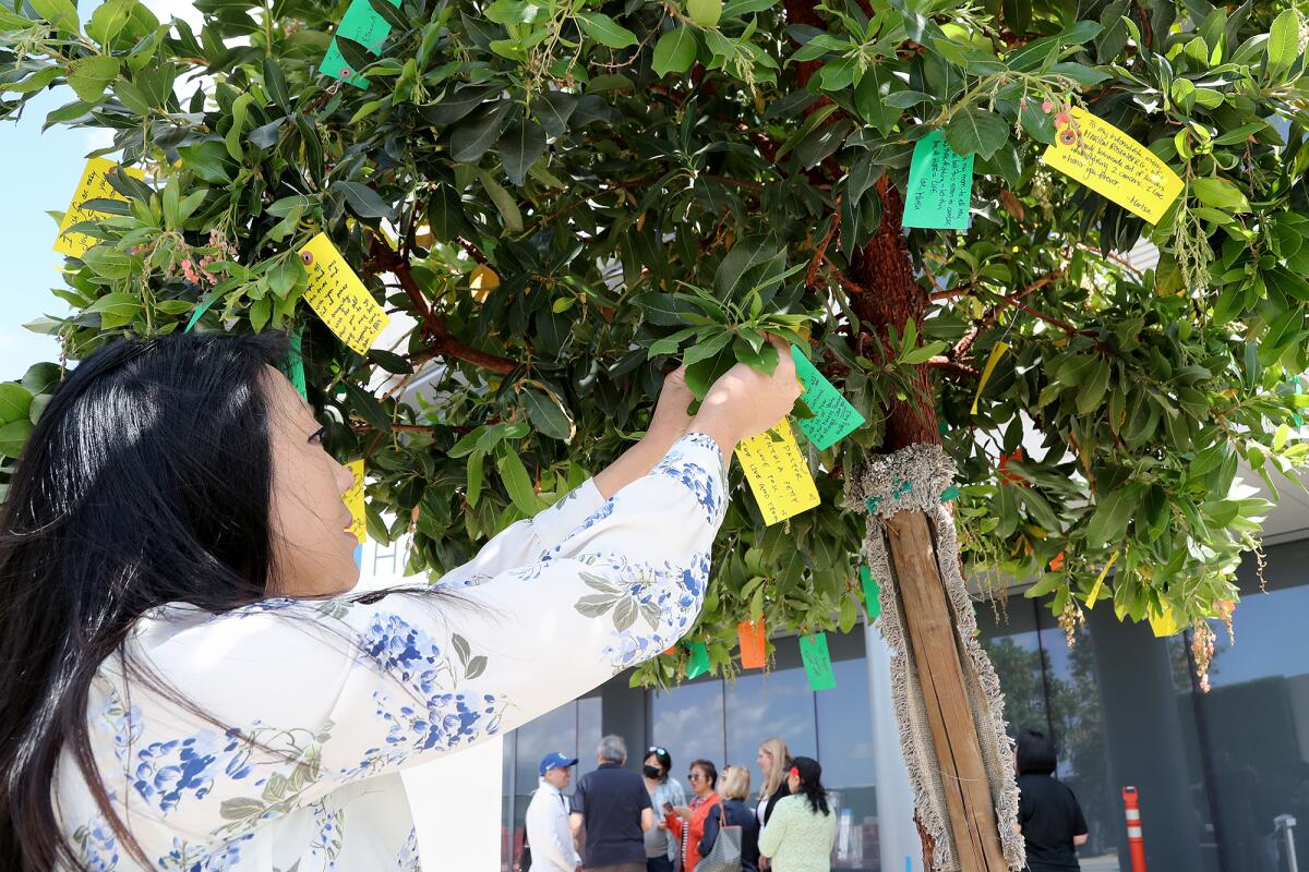 Jennifer Chi adds a wish for her friend, Cynthia Petty, a pastor at Saddleback Church, to the first tree planted.