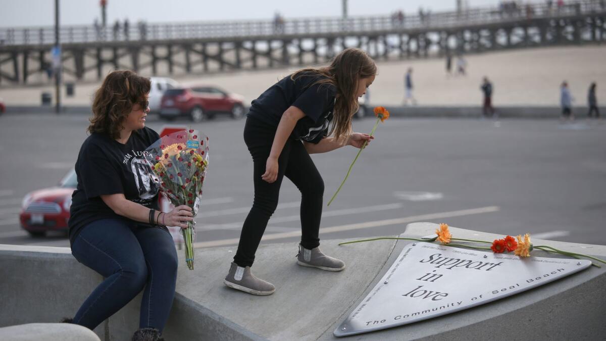 Christina Stretz and her daughter Anabella Stretz, 9, lay flowers on the memorial for the salon victims at Eisenhower Park in Seal Beach on December 10, 2016. Christina lost her sister.