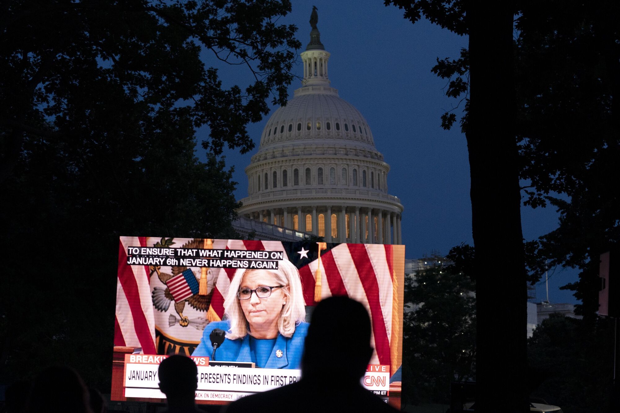 Rep. Liz Cheney appears on a screen as people watch the Jan. 6 hearings near the Capitol