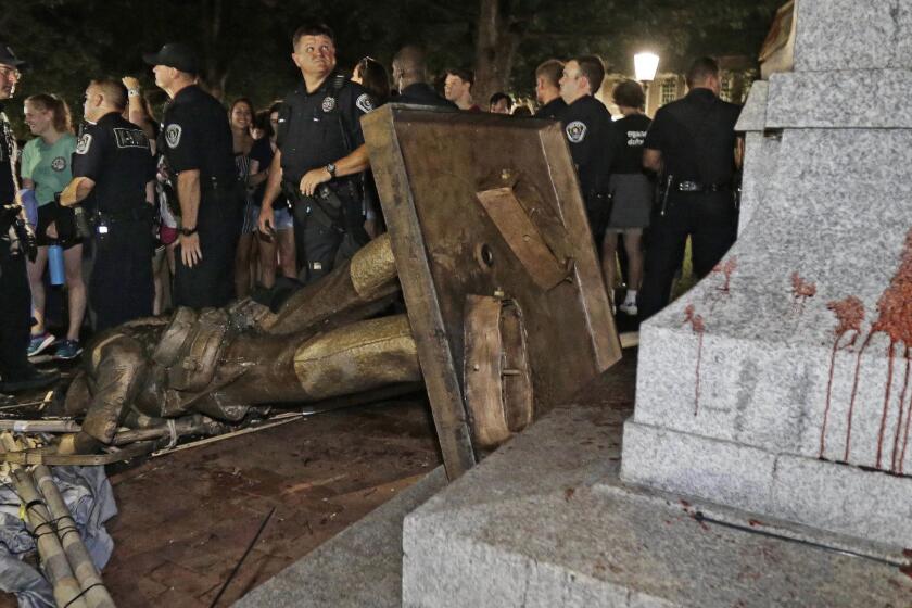 FILE - In this Aug. 20, 2018, file photo, police stand guard after the confederate statue known as Silent Sam was toppled by protesters on campus at the University of North Carolina in Chapel Hill, N.C. Leaders of North Carolinas flagship university are meeting to decide the fate of a Confederate monument torn down by protesters. The chancellor and trustees of the University of North Carolina at Chapel Hill were finalizing a plan Monday, Dec. 3, for the century-old bronze statue known as Silent Sam. (AP Photo/Gerry Broome, File)