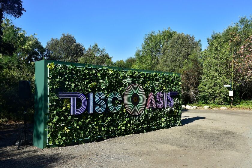   A sign on a backdrop of greenery reads DiscOasis with the "O" styled as a vinyl record