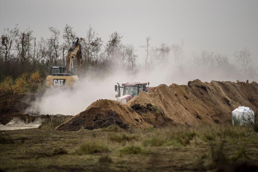 FILE - Heavy machinery is used by members of Danish health authorities, assisted by members of the Danish Armed Forces, in disposing of dead mink in a military area near Holstebro, Denmark, Nov. 9 2020. A Danish Parliament-appointed commission on Thursday June 30, 2022, has harshly criticized the country's government for its decision to cull millions of healthy mink at the height of the coronavirus pandemic to protect humans from a mutation of the virus. (Morten Stricker/Ritzau Scanpix via AP, File)