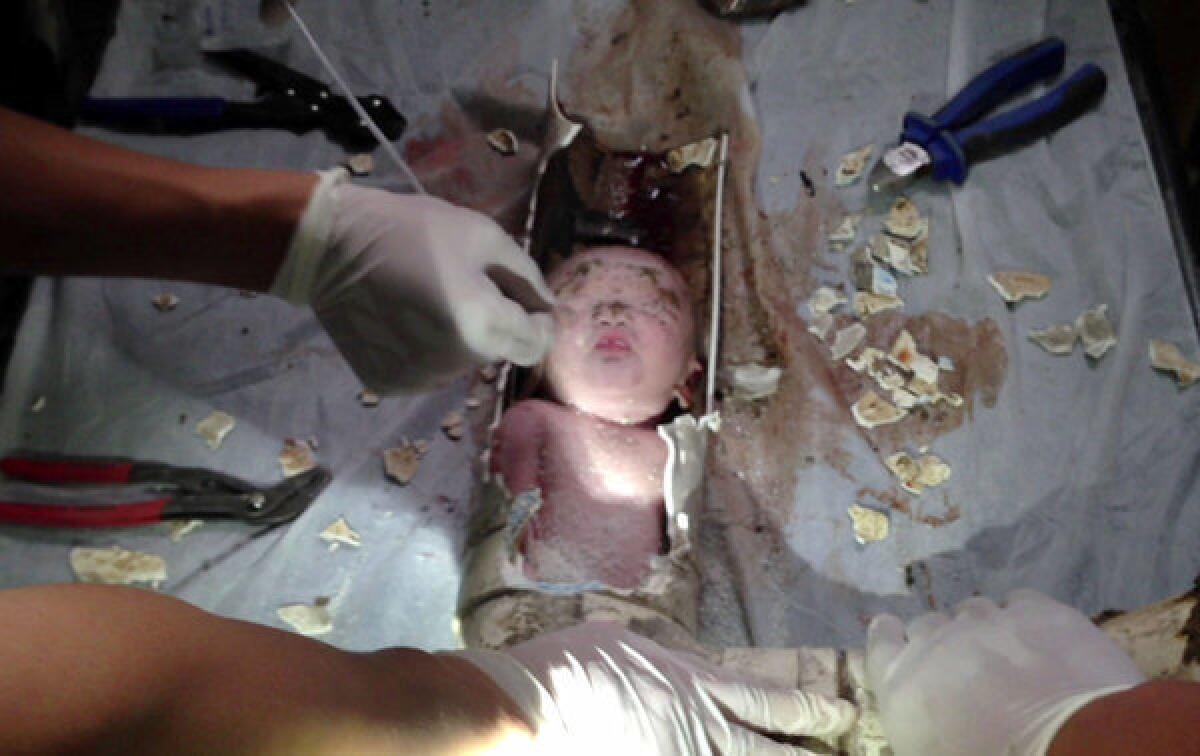 Rescue workers break away bits of a sewer pipe to remove a newborn boy. The baby's 22-year-old mother reportedly told police the child slipped into the pipe after being delivered in a toilet.