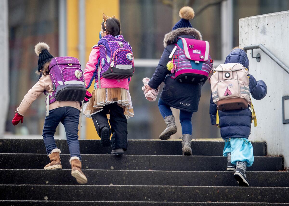 Children in backpacks and winter clothes climb stairs.